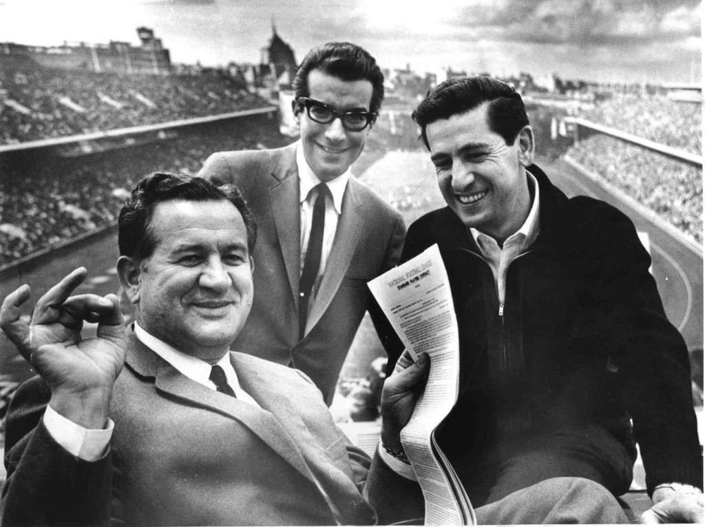 Eagles coach Joe Kuharich smiling over new contract given to him by new Eagles owner Jerry Wolman. VP Ed Snider in the background